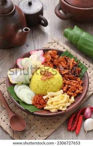 Nasi kuning or sometimes called nasi kunyit (Indonesian for: "turmeric rice"), is an Indonesian fragrant rice dish cooked with coconut milk and turmeric, hence the name nasi kuning (yellow rice). Royalty-Free Stock Photo #2306727653