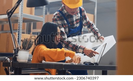 Asian woman with impairment looking at packages in storage room, analyzing products in boxes before sending order. Female worker in wheelchair planning shipment, business plan. Handheld shot.