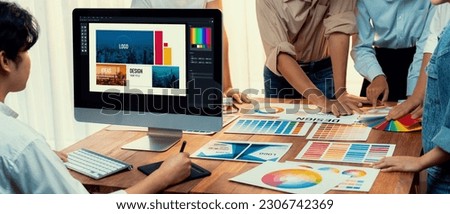 Graphic designer work on computer laptop and with graphic drawing pen while brainstorming unique design with professional graphic team in modern digital studio workplace. Panorama shot. Scrutinize Royalty-Free Stock Photo #2306742369