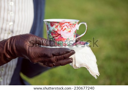 Vintage lady holds cup of tea on a picnic 