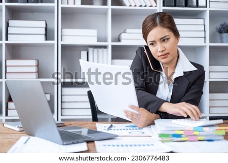 Young busy businesswoman working at office, Young Business woman with documents calling phone and calculate with calculator Royalty-Free Stock Photo #2306776483