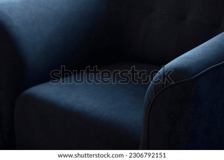 Upholstered furniture made of velor blue fabric with rounded elbows close-up. An element of upholstered furniture with a stitched sidewall in deep shadows with an empty space for text with copy space. Royalty-Free Stock Photo #2306792151