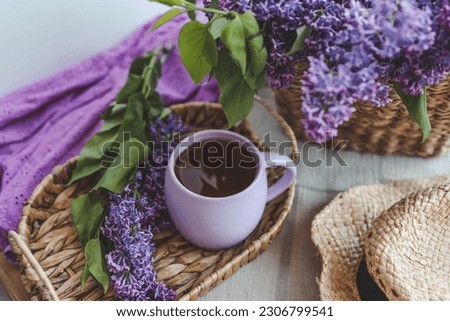 Cup of tea, straw hat and lilac basket, spring still life.