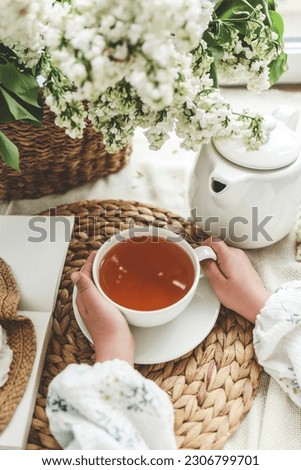 A cup of tea in hands on a background of lilac, top view, aesthetic photo.