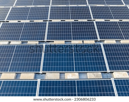 Aerial photo solar panels install on a flat commercial, industrial roof, with concrete blocks.
