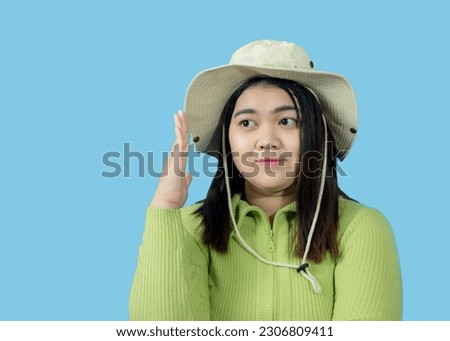 Portrait girl young woman asian chubby fat cute beautiful pretty one person wearing a green shirt hat is sitting smiling enjoy happily looking wow to copyspace imaginary on the blue background