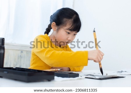 A child learning japanese calligraphy practices writing "Japan". Royalty-Free Stock Photo #2306811335