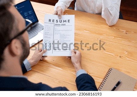 Candidate handing resume or CV over table to interviewer in corporate meeting room. Job applicant show her qualification and work experience to HR manager with digital resume on laptop screen. Entity