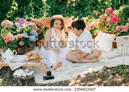 Happy kids boy and girl romantic picture in the park picnic with summer flowers. Boy and girl