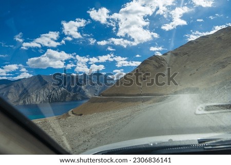 view of beautiful landscape of the road, mountain and Pangong lake from the interior of cars