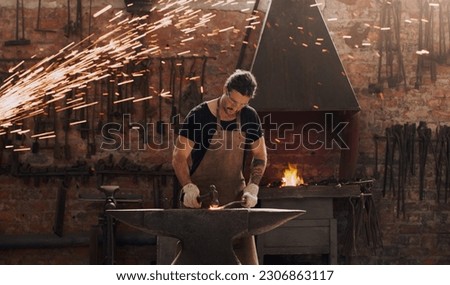 Hammer, anvil and fire with a man working in a plant for metal work manufacturing or production. Industry, welding and trade with a male blacksmith at work in a factory, forge or industrial workshop Royalty-Free Stock Photo #2306863117