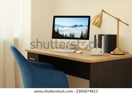 Cozy workspace with computer on wooden desk and comfortable chair at home