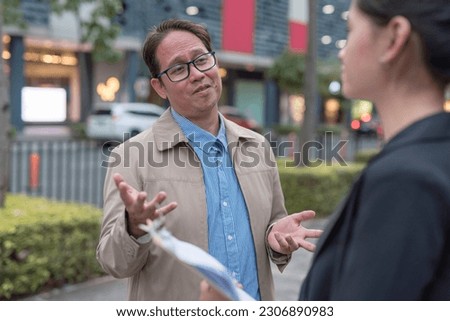 An arrogant boss cockily tells his secretary what to do while taking a walk at the park. Royalty-Free Stock Photo #2306890983