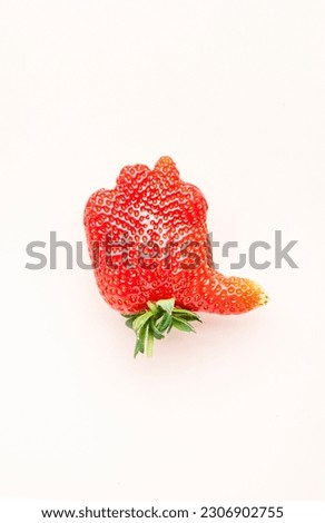 Unusual strawberry in the shape of hand with thumb up similar the like sign, beige background, top view