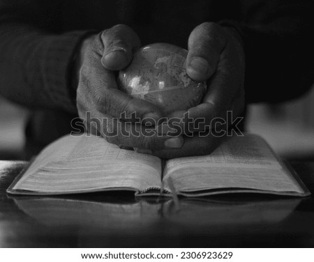 man with bible and globe praying to god on black background with people stock photo