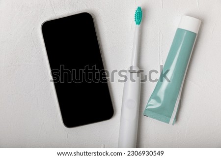 Sonic electric toothbrush with wireless connection to a smartphone app on a white marble background. Modern home technology concept. Oral and gum care. Medicine concept. Dentist.