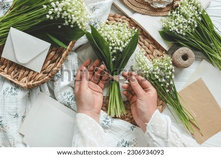Girl florist holds a bouquet of lilies of the valley in her hands.
