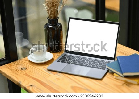 Comfortable workplace with laptop, cup of coffee and books on wooden table