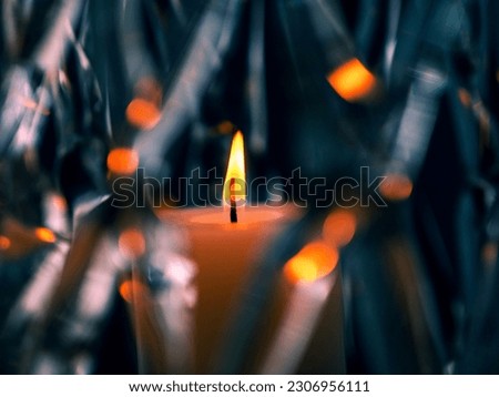 Burning orange candle in a glass mesh vase. Warm and cool color scheme. Abstract art.