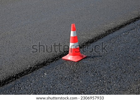 orange cone on new asphalt road