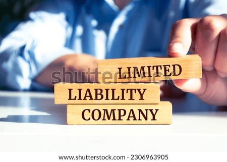 Close up on businessman holding a wooden block with "Limited Liability Company" message Royalty-Free Stock Photo #2306963905