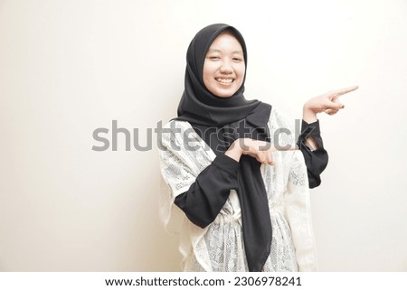 Portrait of excited Asian girl hijab smiling and looking at the camera pointing with two hands and fingers to the side. Isolated image on white background