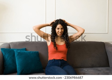 Upset stressed young woman scratching her curly hair and feeling itchy while suffering from lice 
