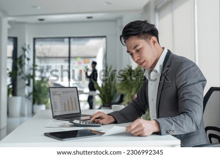young business man look at laptop screen calculate expenses expenditures pay bills taxes online. male busy managing company budget, take care of financial paperwork Royalty-Free Stock Photo #2306992345