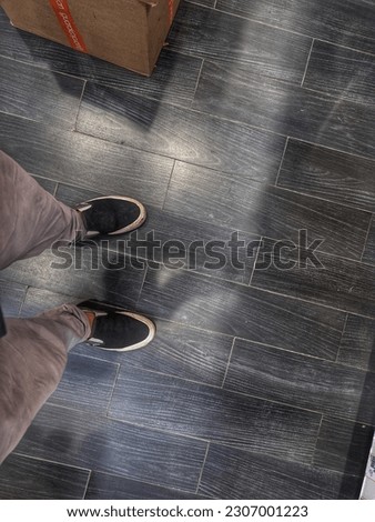 standing feet wearing casual shoes on a black wooden textured floor