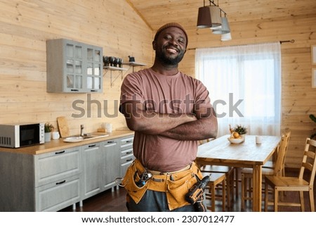 Young cheerful African American repairman or plumber with toolbelt keeping his arms crossed by chest and looking at camera with smile Royalty-Free Stock Photo #2307012477