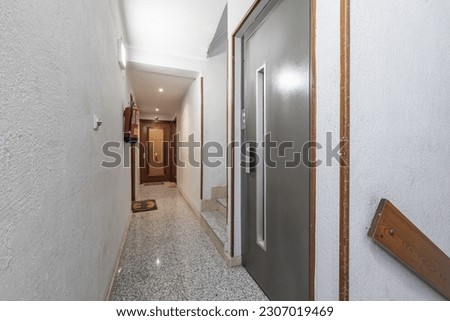 A narrow hallway on the landing of a residential building with a simple elevator and stairs with a wooden railing Royalty-Free Stock Photo #2307019469
