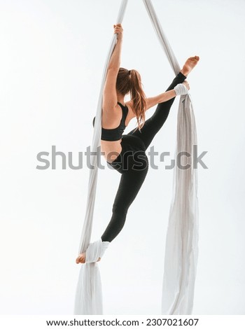 Conception of flexibility. Young beautiful woman doing fly yoga against white background.