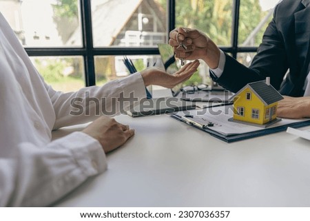 Agent giving client new house key in office The happy man has received the keys to his new house. Close-up shot of a real estate agent's hands at