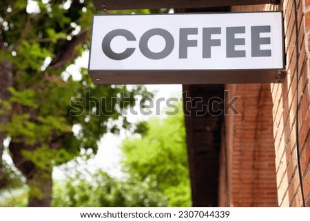 Black and white coffeehouse commercial sign with a word Coffee on a city street. Cafe advertisement lightbox hanging next to the entrance