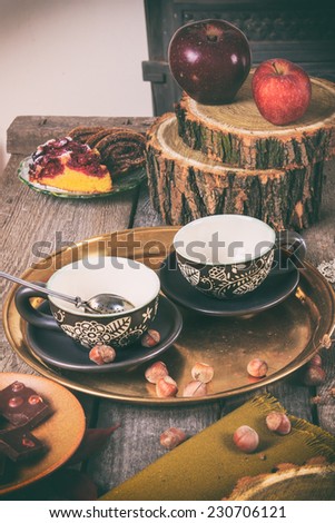Tea equipment on vintage kitchen table with cups homemade cookies chocolate and apples