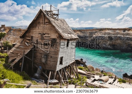 Old abandoned house on the edge of a cliff overlooking the sea and cliffs in the background Royalty-Free Stock Photo #2307063679