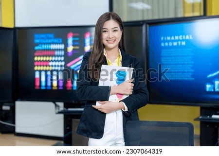 Successful businesswoman standing in creative office and looking at camera. Woman entrepreneur in a coworking space smiling. Portrait of beautiful business woman standing