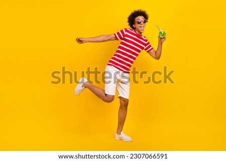 Full length photo of pretty funky man wear striped t-shirt drinking cocktail having fun isolated yellow color background Royalty-Free Stock Photo #2307066591