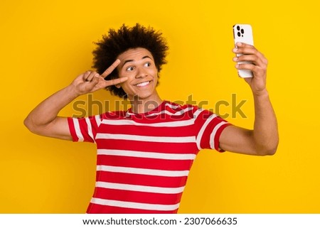 Photo of funky handsome person hold smart phone show v-sign make selfie isolated on yellow color background