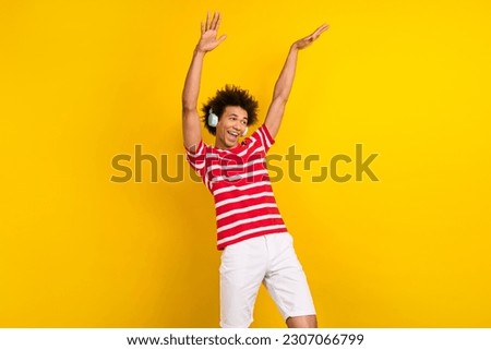Photo of cool cheerful man wear striped t-shirt listening headphones having fun isolated yellow color background