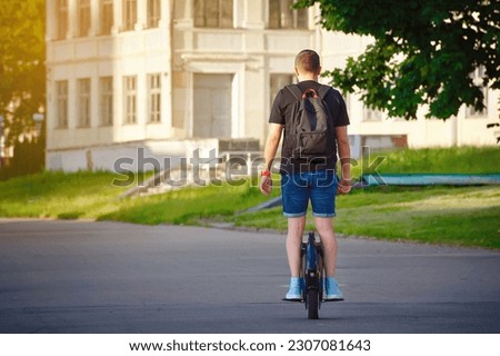 Man riding fast on electric unicycle in city street. Mobile individual transportation vehicle. Boy on personal electric vehicle for self transportation. Man with backpack on mono-wheel 