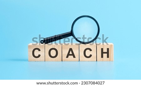 wooden cubes with the text: coach and magnifying glass, blue background. business concept