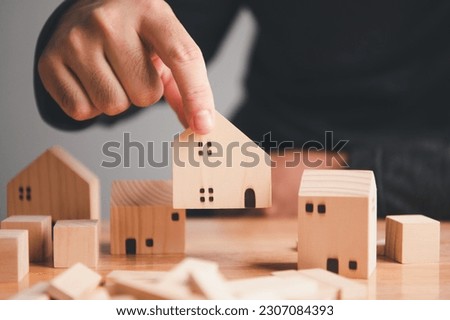 The property management team planning to manage real estate projects and private luxury villages by hand. Man arranging wooden house model on the table. Business and living life concept. Royalty-Free Stock Photo #2307084393