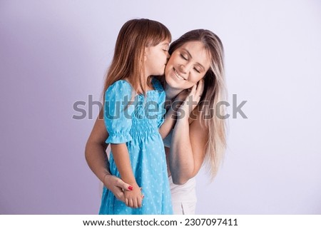 little daughter gives a kiss on her mother's cheek isolated on white background