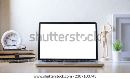 Laptop computer, coffee cup, potted plant and picture frame on creative workplace. Blank screen for your advertise text.