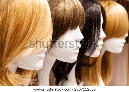 Multi-colored wigs are worn on the heads of mannequins. Royalty-Free Stock Photo #2307112555