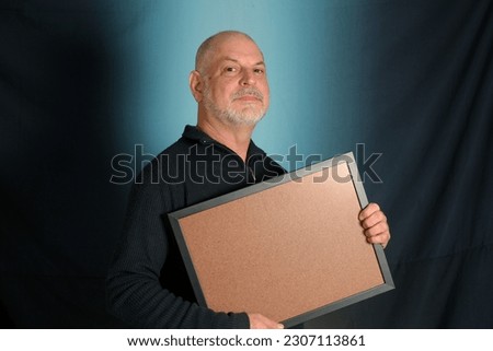 white bearded man holding advertisement board, advertising board, gentleman in black shirt colored background