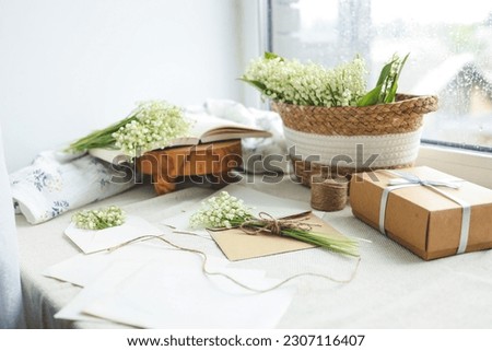 Festive concept, lily of the valley bouquet, gift box and letter.