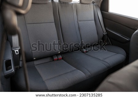 Close-up on rear seats with velours fabric upholstery in the interior of an old Korean car in gray after dry cleaning. Auto service industry. Royalty-Free Stock Photo #2307135285