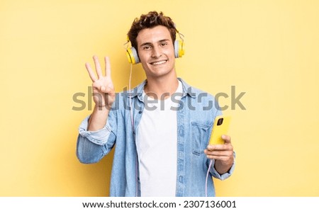 smiling and looking friendly, showing number three or third with hand forward, counting down. headphones and smartphone concept